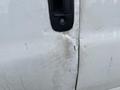 Close-up of a dent on the side door of a 2014 GMC Savana with scratches and marks on the white paint