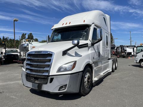 A white 2022 Freightliner Cascadia semi-truck with a sleek design and a prominent front grille is parked in an open area