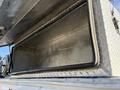 A silver metal storage compartment of a 2009 Ford F-550 with a textured surface and an open lid revealing an empty interior
