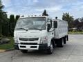 A 2014 Mitsubishi Fuso FE truck with a white body and grey details without a cargo load parked on a paved surface