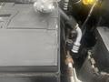 A close-up view of a 2004 Ford Econoline's engine components including a battery and various metal pipes and connections