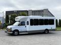 A 2020 Chevrolet Express bus with a white and gray exterior and large windows parked at a facility