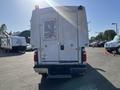 A white 2014 Ford F-350 SD with a utility box attached to the back is parked with its tailgate visible