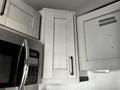 A modern kitchen with light-colored cabinets and a microwave featuring a digital display and control panel