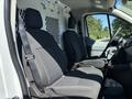 The interior of a 2016 Ford Transit showing two black fabric front seats with a mesh divider behind them