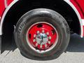 Close-up of a large tire from a 2006 Emergency One Fire Truck showing a shiny red wheel and visible reflection of a person in the hubcaps