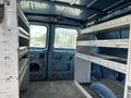 Interior of a 2009 Ford Econoline van featuring metal shelving units on both sides and ample cargo space on the floor