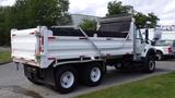 A 2014 International 7500 truck with a dump bed and a white body showing red and silver striping