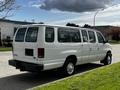 A white 2004 Ford Econoline van with a sliding side door parked on the street, showcasing its rear and side profile