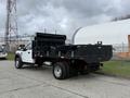 A 2021 Ford F600 truck with a black flatbed and a tarp on the back parked on a concrete surface