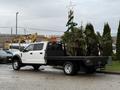 A white 2022 Ford F-550 flatbed truck with a black bed and a rear cab protector is parked in a lot