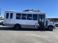 A white 2020 Chevrolet Express bus with large windows and side entry doors parked on a paved surface