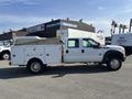 A white 2015 Ford F-450 Super Duty truck with a utility bed and tool compartments on the sides