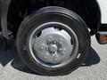 A close-up of a silver wheel with a black tire showcasing the tread pattern and lug nuts
