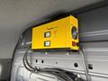 A yellow power inverter mounted on the wall inside a vehicle with two digital displays and a fan on the side