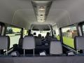 Interior of a 2023 Mercedes-Benz Sprinter featuring multiple black seats arranged in rows with overhead lighting and a spacious layout