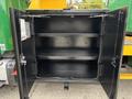 An open black storage compartment with two metal shelves and hinged doors designed for a 2015 Freightliner M2 106 truck