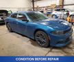 A blue 2022 Dodge Charger with a sleek design and black wheels is parked in an indoor setting showing signs of wear and tear before repair
