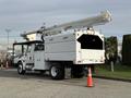 A 2011 International 4300 truck with a bucket lift extended on top and a white utility body designed for maintenance and service tasks