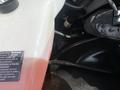 A close-up view of the engine compartment of a 2022 GMC Savana showing a coolant reservoir and various engine components