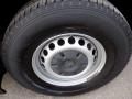 A close-up of a wheel and tire of a 2016 Mercedes-Benz Sprinter showing a silver steel rim with circular cutouts and a black tire with tread patterns
