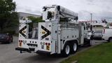 A 2012 International 7400 truck with a bucket lift mounted on the back and storage compartments on the sides