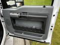 The interior door panel of a 2016 Ford F-550 featuring a gray plastic finish with a pull handle and storage compartment