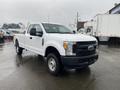 A white 2017 Ford F-250 Super Duty pickup truck with a crew cab and a black front grille parked on a wet surface