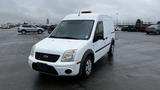 A white 2012 Ford Transit van with a yellow light on the roof parked in a lot