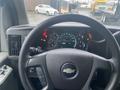 The interior of a 2012 Chevrolet Express showing the steering wheel and dashboard with gauges and warning lights illuminated