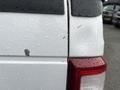 A close-up view of the rear of a white 2010 Ford F-250 SD displaying water droplets on the surface and a small mark on the paint near the taillight