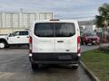 A white 2023 Ford Transit van viewed from the rear with a simple design and rear lights visible