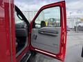 A red 2007 Ford F-550 with the driver's side door open revealing a gray interior and dashboard details