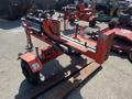 A 2021 Wallenstein Wx540-0RA tow-behind industrial log splitter in red with two units, featuring a hydraulic system and wooden supports for splitting logs