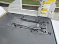 Two black straps are attached to a gray rubber surface in the rear of a 2009 Toyota Hiace designed for securing cargo or wheelchairs