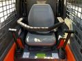 The interior of a 2017 Gehl R105 with a gray seat and adjustable levers on either side for operation