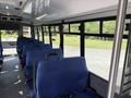 Interior of a 2020 Chevrolet Express bus featuring rows of blue seating with seatbelts and a clean, modern design