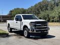 A white 2020 Ford F-350 Super Duty truck with chrome accents and a black hood ornament parked on a paved area with shiny wheels and a clean exterior