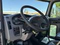The interior of a 2019 Peterbilt 337 featuring a black steering wheel a dashboard with gauges and control buttons and leather seats