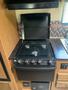 A black outdoor grill with four control knobs and a folding lid designed for use with a 2014 Launch 24RLS camper
