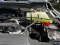 Close-up view of the engine compartment of a 2024 Ford F-550 featuring various components including hoses and a coolant reservoir