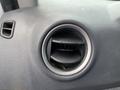 A close-up of a circular air vent from a 2010 Ford Transit Connect with a textured black surface and adjustable slats in the center