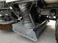 Close-up of a 2012 Autocar Xpert's undercarriage showing a large circular vacuum attachment with flexible hoses and metal chains securing it to the main body of the vehicle