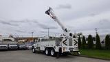 A 2012 International 7400 utility truck with an extended boom and bucket positioned for aerial work