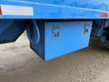 A blue storage box mounted beneath a 2011 Freightliner Cascadia Nordic truck with metal latches and visible wear marks