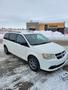 A white 2012 Dodge Grand Caravan with alloy wheels is parked on a snowy surface