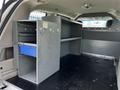 Interior view of a 2011 Dodge Grand Caravan with metal storage units and shelves installed in the cargo area