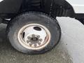 Close-up of the wheel and tire of a 2012 Ford Econoline showing a silver rim with multiple bolt holes and a black tire with a rugged tread pattern