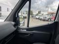 Interior view of a 2025 Mercedes-Benz Sprinter van featuring a sleek dashboard a modern steering wheel and a clear side mirror showcasing the vehicle's spacious design