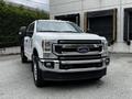A white 2020 Ford F-350 Super Duty with a chrome grille and black accents facing the viewer with large tires and a robust build